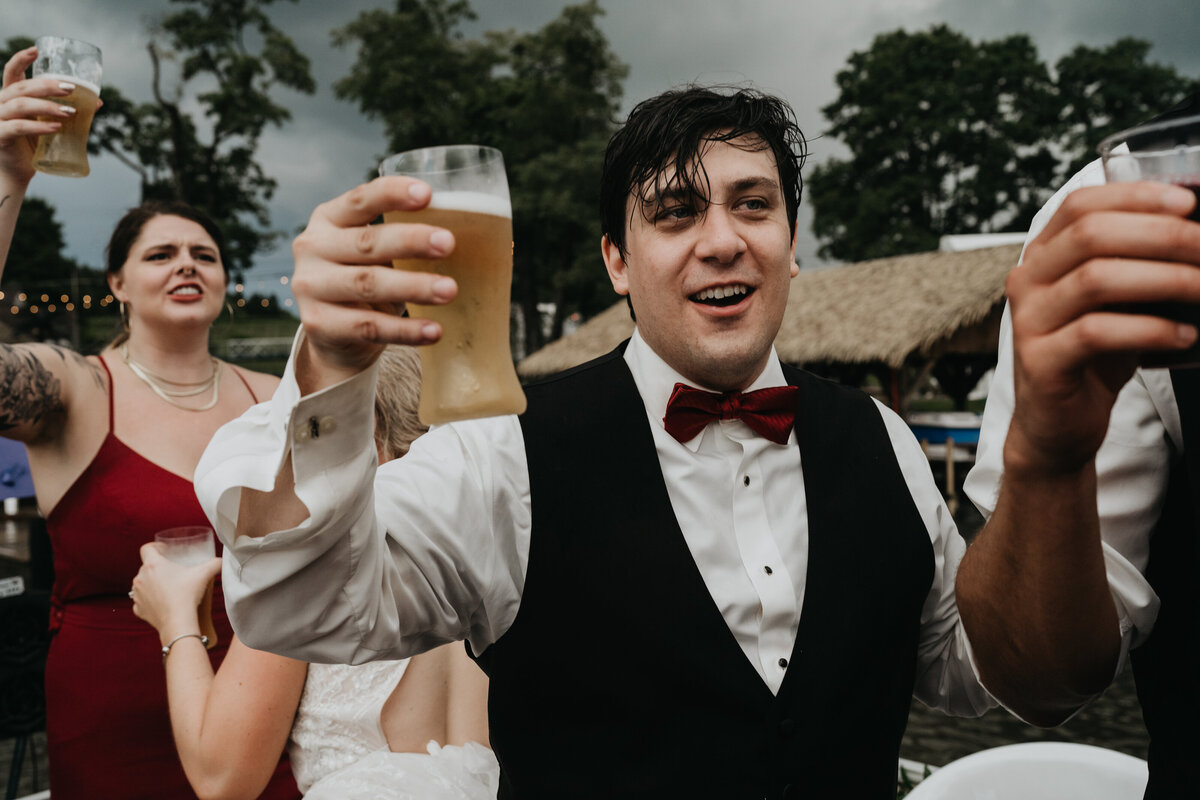 Groom drinks a beer on a boat in Geauga County wedding reception