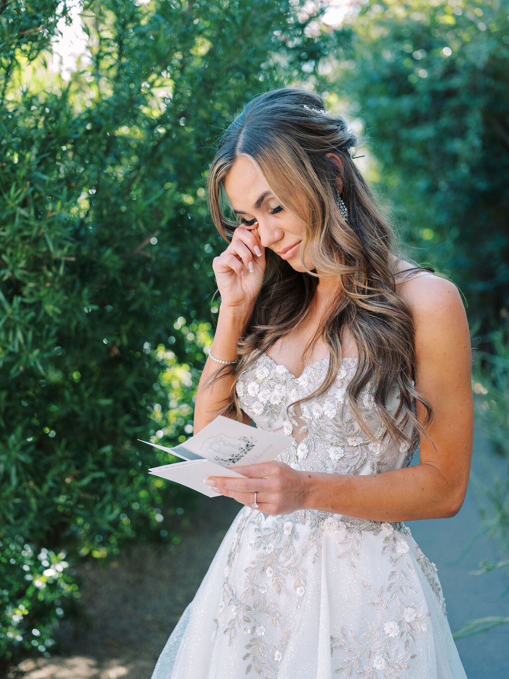 A beautiful bride captured in a candid moment reading her wedding vows, overcome with emotion on her special day.