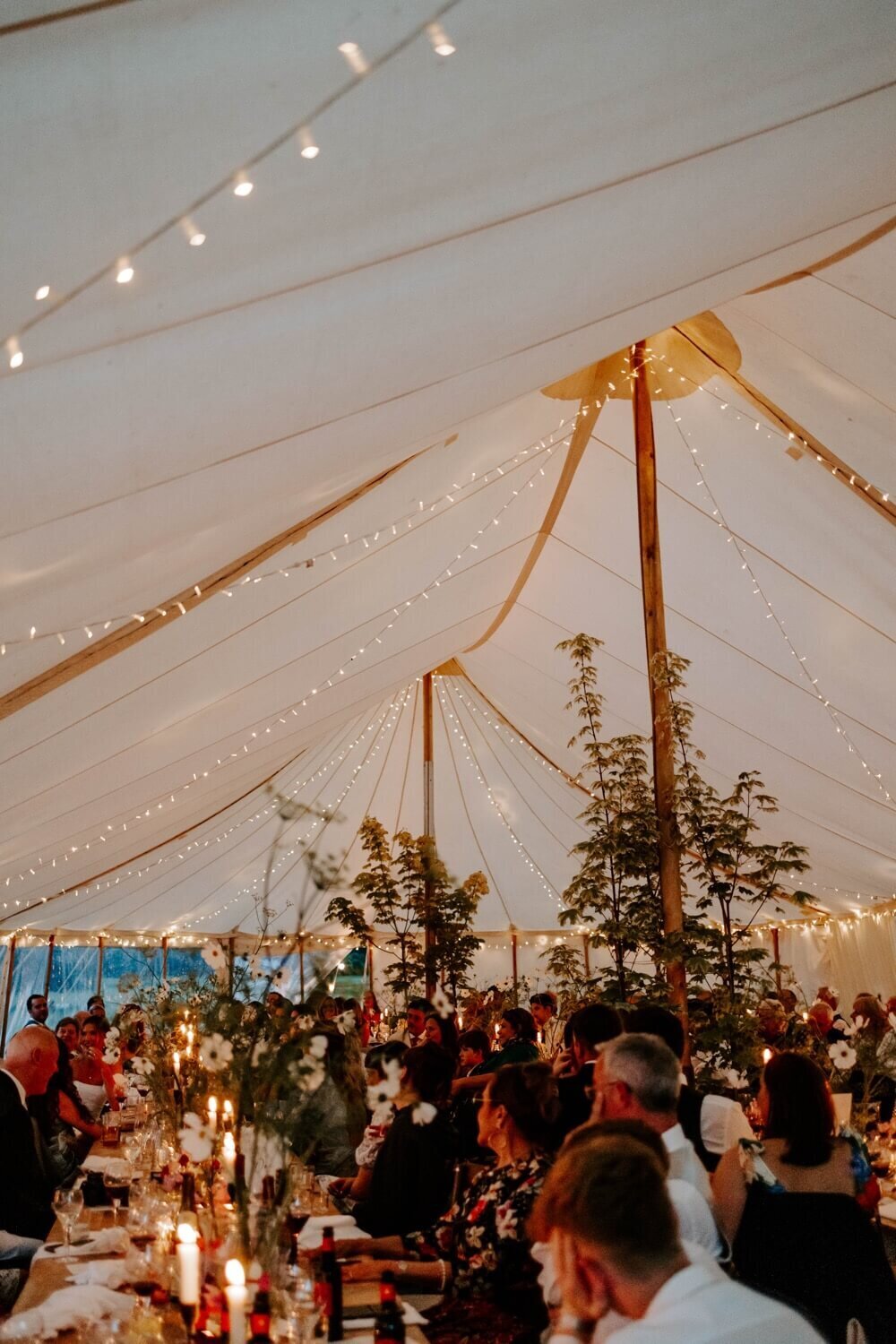 A wedding breakfast in a pole marquee with people eating and enjoying the evening