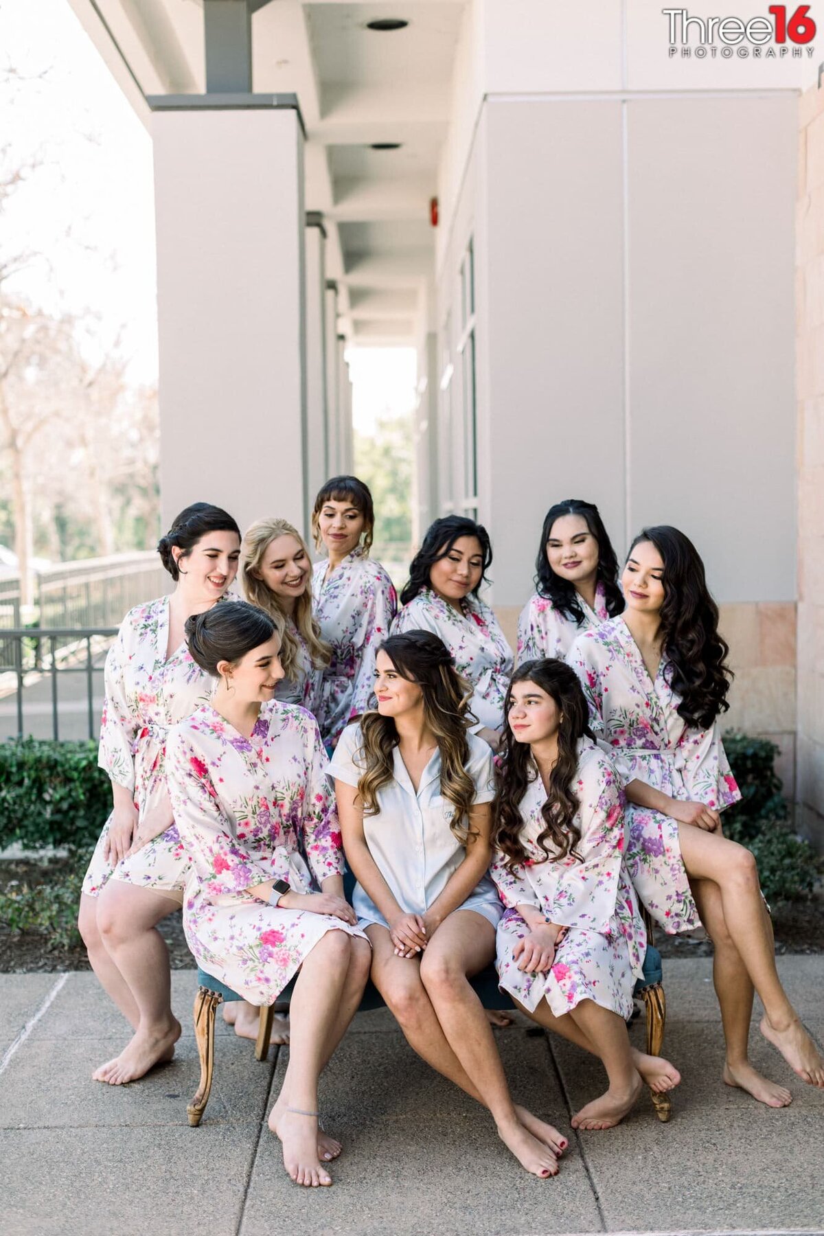 Bride and her Bridesmaids sit outside together wearing their pre-wedding robes
