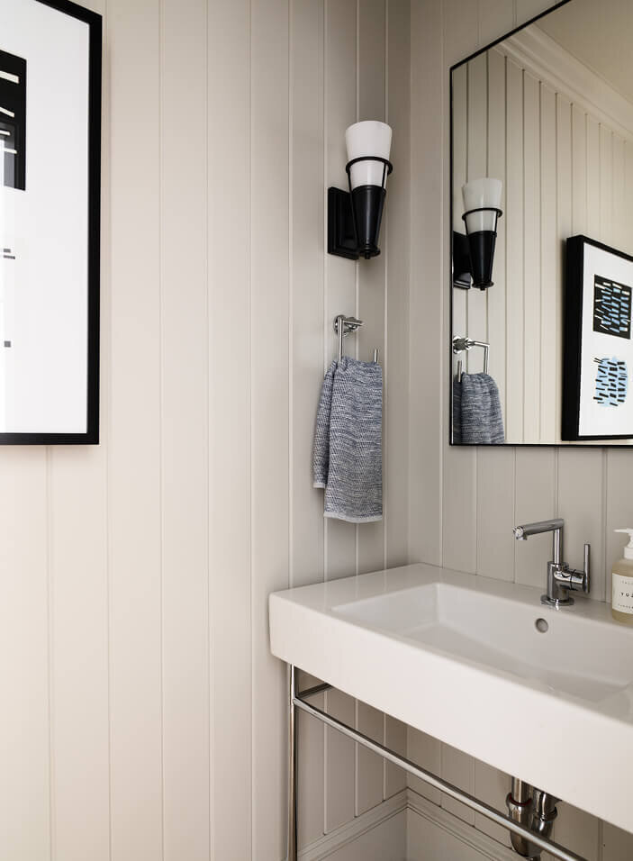 Powder room interior design with light grey shiplap walls and a white ceramic sink, blending soft textures with clean, timeless design elements.