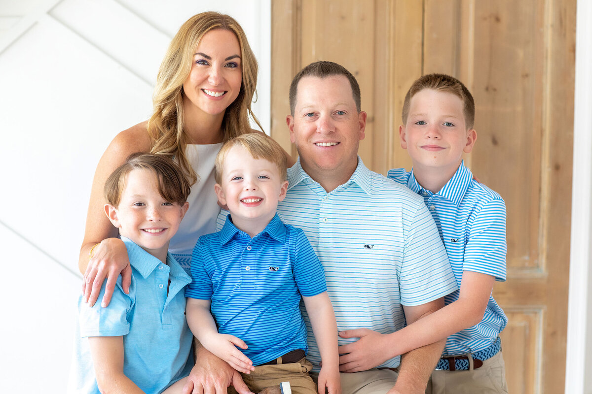 Family of five dressed in coordinating blue outfits during a Bucks County family photo session, smiling and posing together