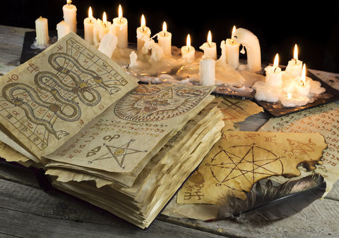 Photo of candles burning next to a magical  witchcraft course book