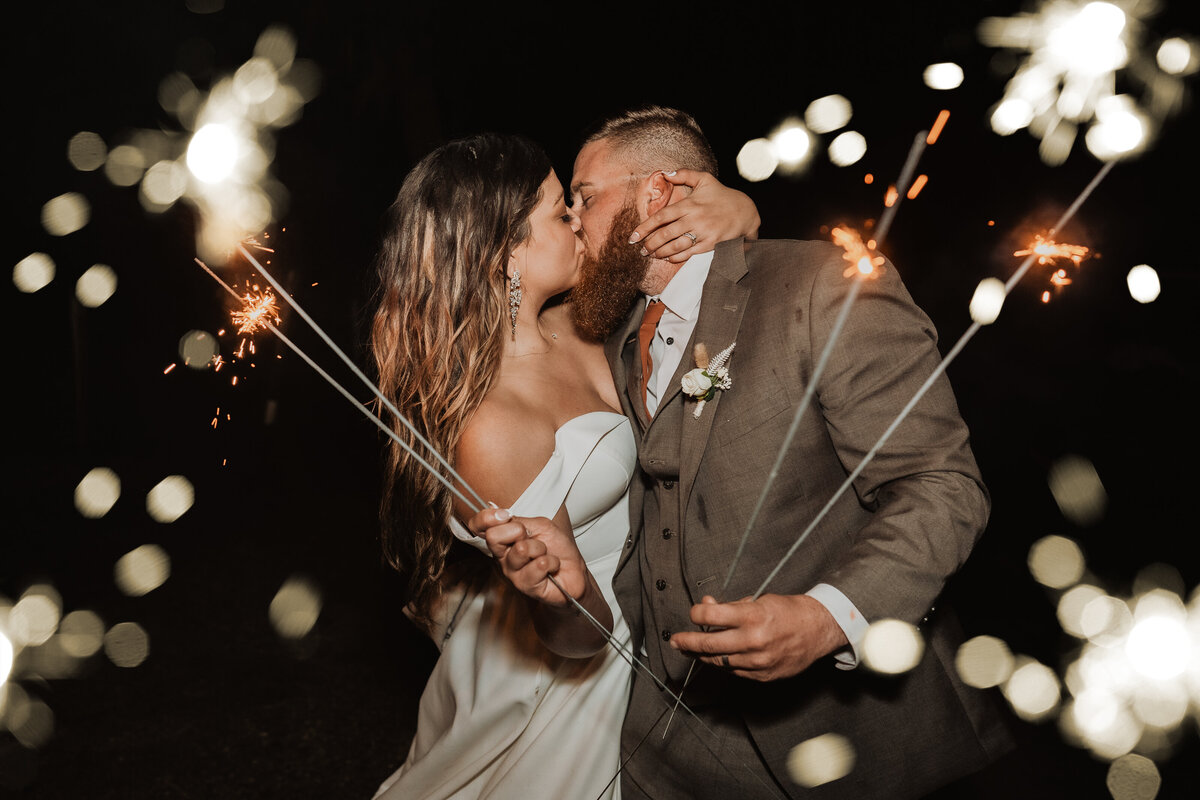 bride kissing groom holding sparklers