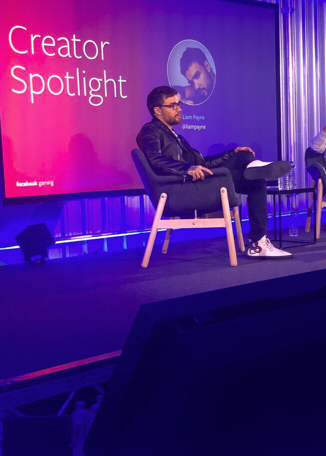 Liam Payne being interviewed for an event for Facebook Gaming on a purple lit stage.