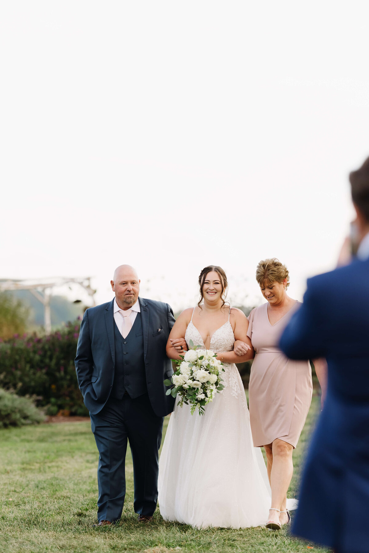 Charlottesville wedding photographer captures bride being walked down the aisle with her parents escorting her for her outdoor ceremony at Sunny Slope Farm
