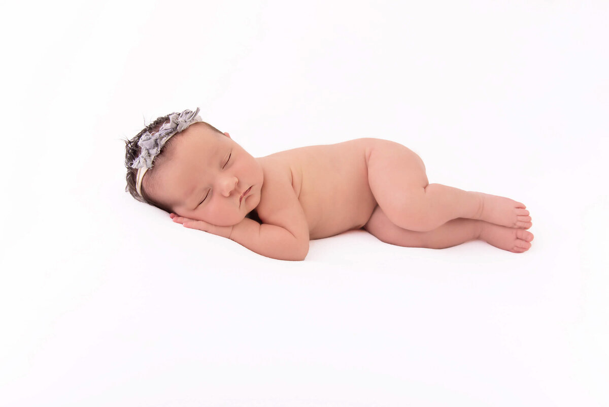 newborn girl laying on her side on a white background for her newborn photos in Burlington, ON