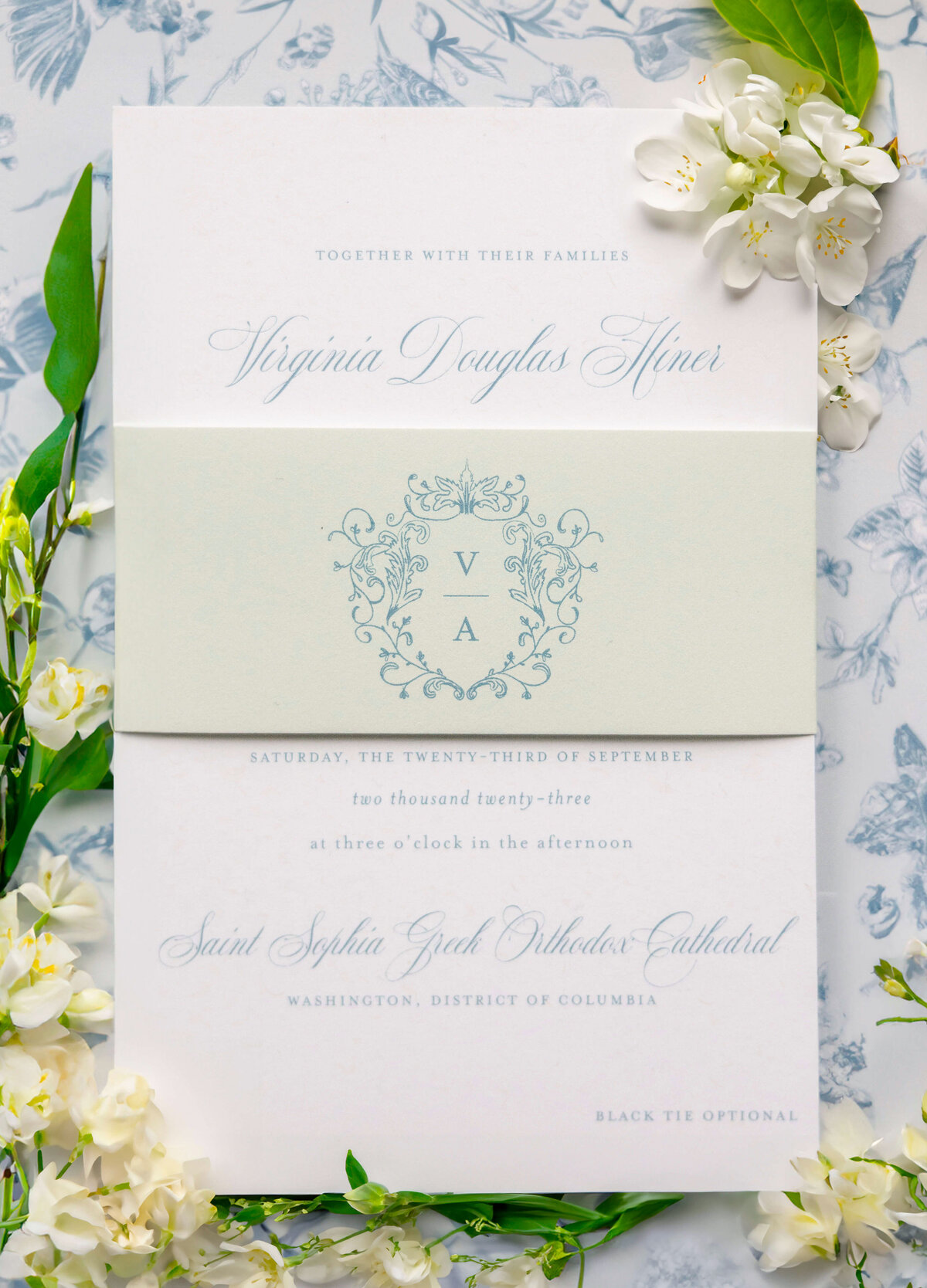 A wedding invitation with elegant floral border and delicate script text. Virginia Douglas Finer is the main name, with event details for Saturday, the 23rd of September at Saint Sophia Greek Orthodox Cathedral in Washington, D.C.