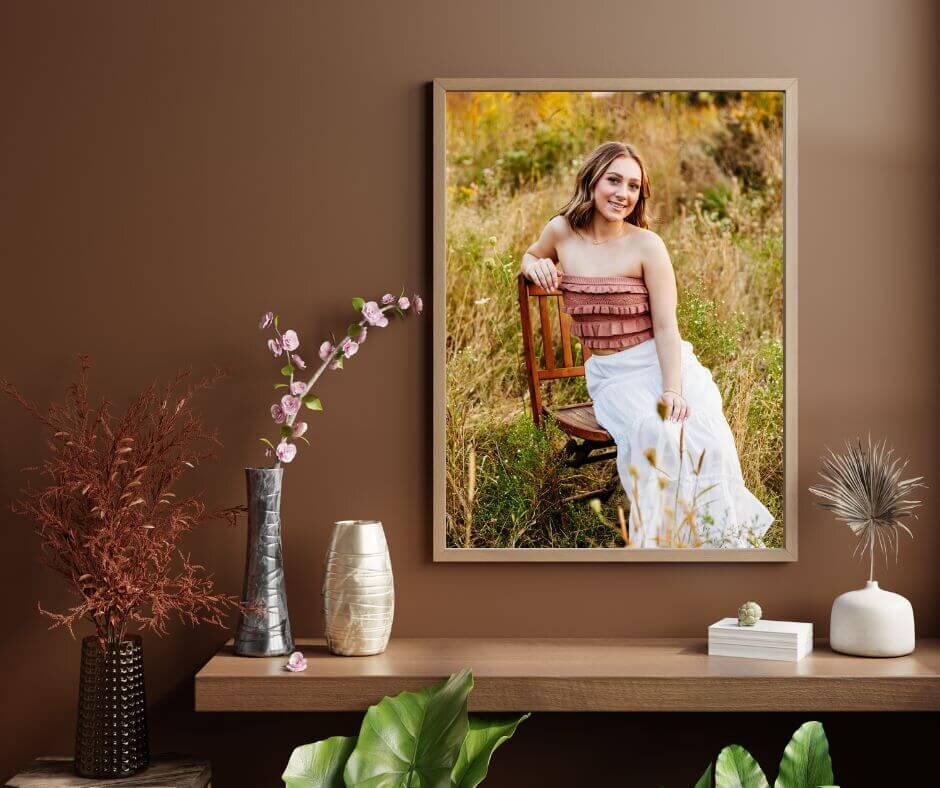 senior photo hanging in a wooden frame on a brown wall above a shelf.