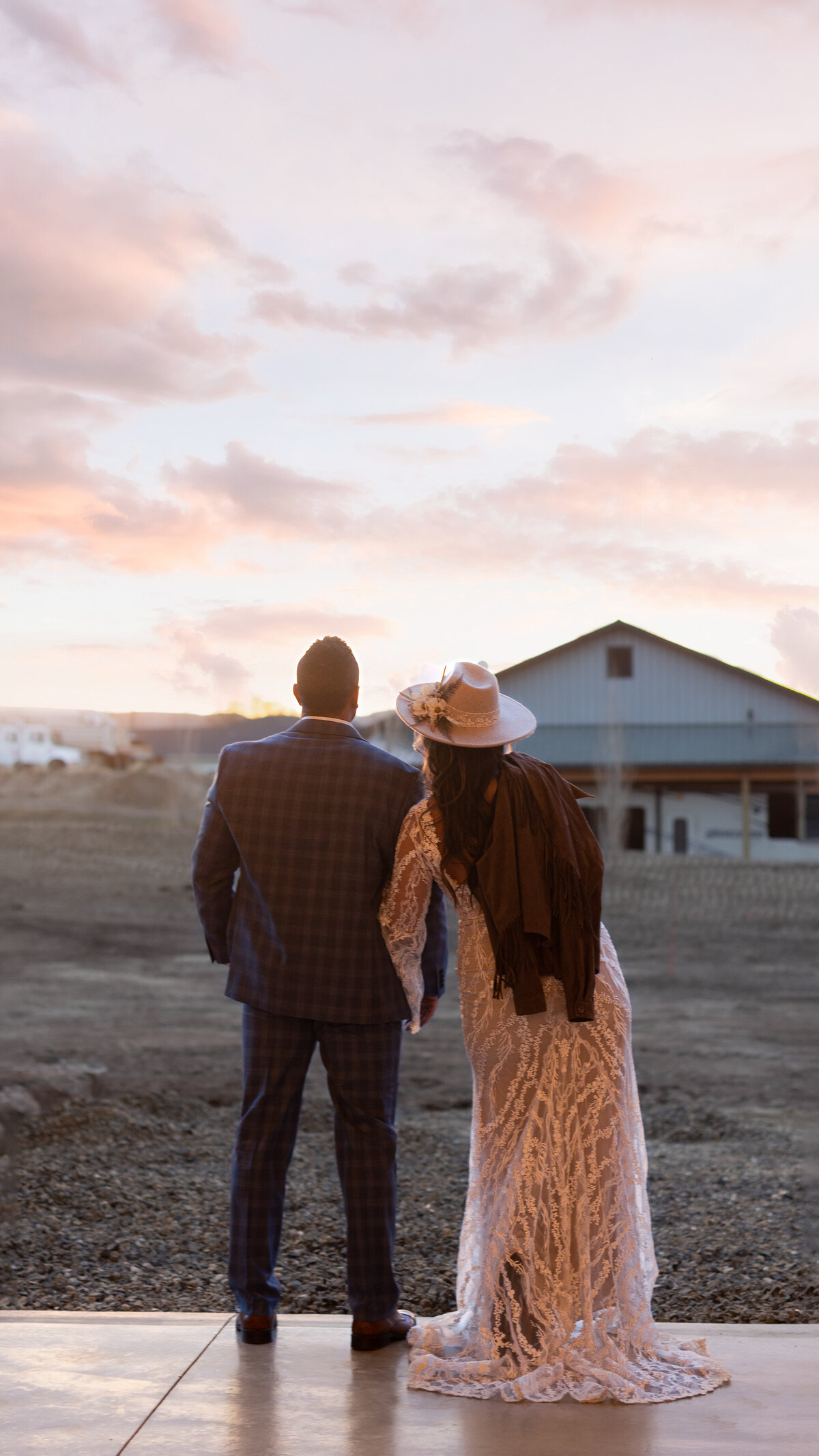 Couple standing overlooking the farm. She's wearing the hat.