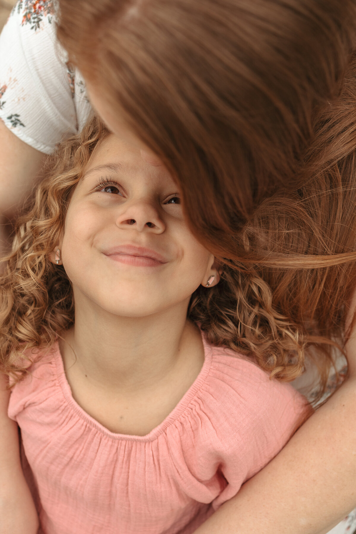 little girl looking up at mom while mom is kissing her forehead during family session in firestone colorado