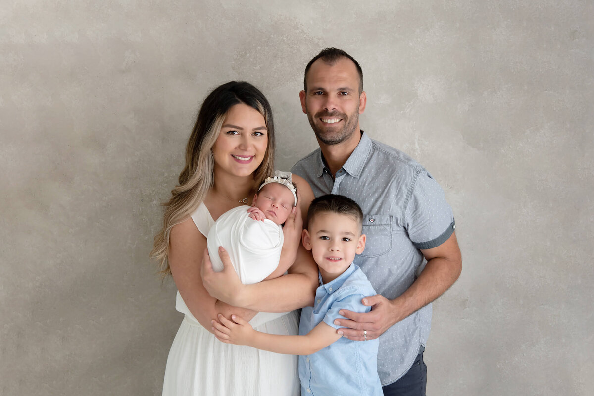 Family newborn photography photo of mom and dad with their older son and newborn baby girl