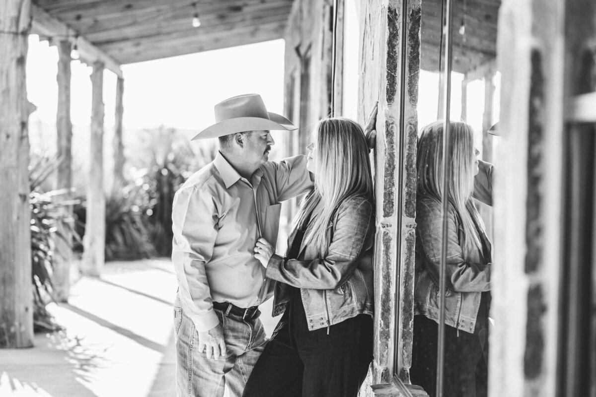 black and white photo of husband and wife leaning against window at El Cerrito Lodge in New Diana, TX