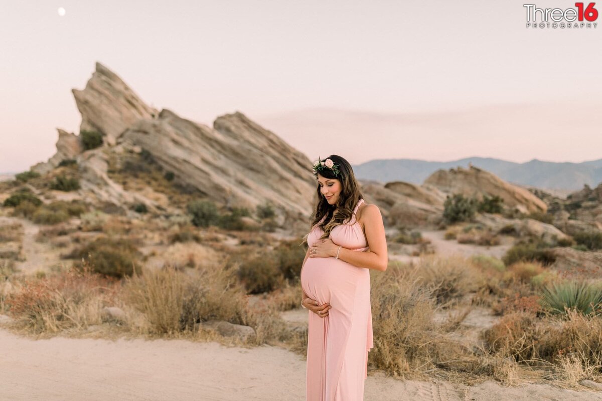Mom to be poses for photos caressing her unborn child that she is carrying at Vasquez Rocks