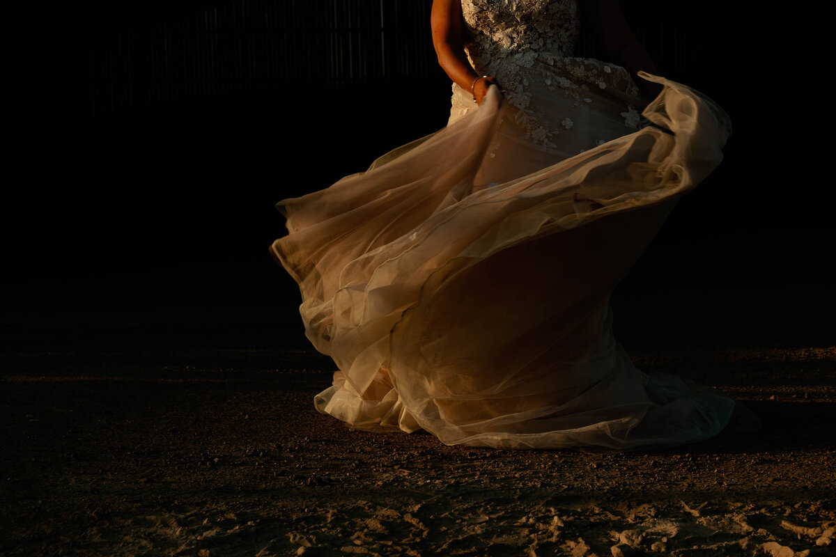 Bride swishing her dress in the direct sunset light