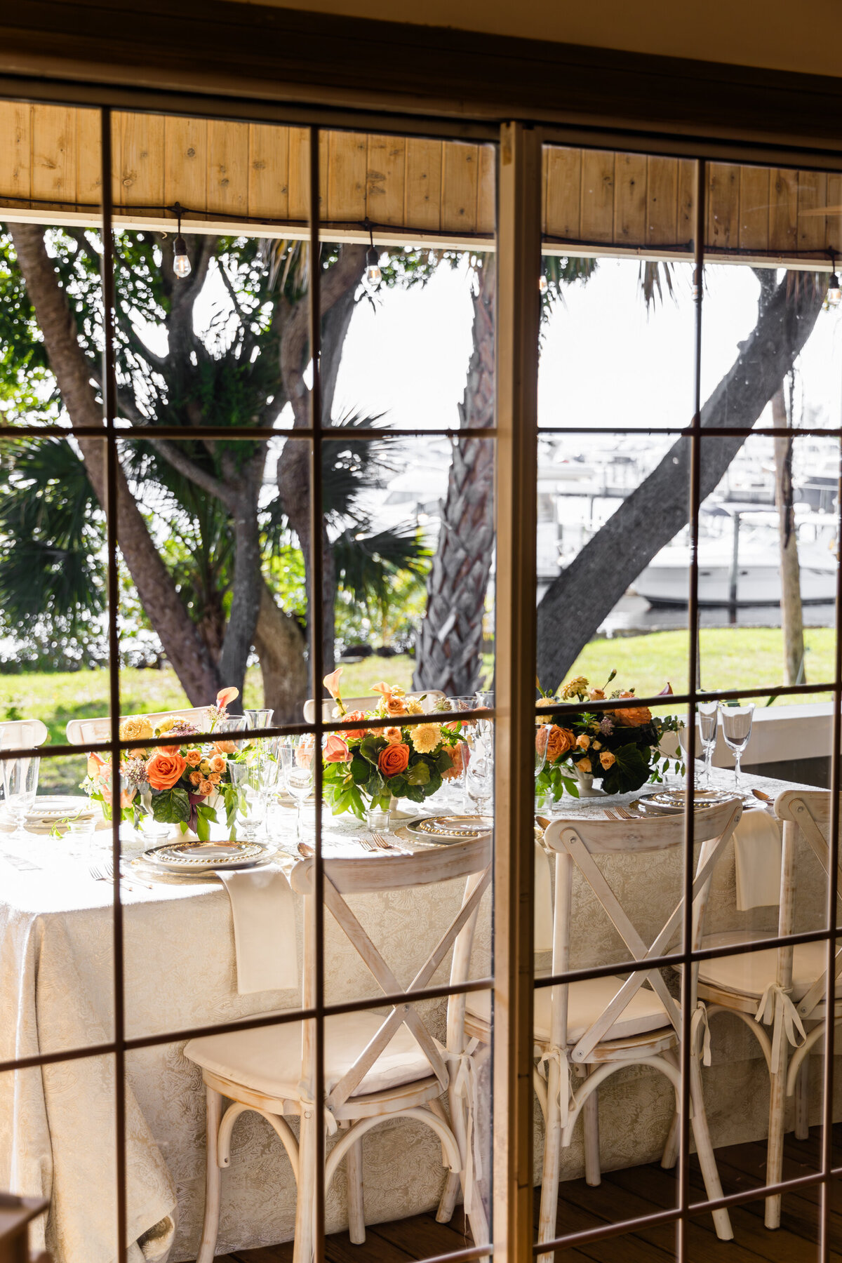 window view of table set with mixed metals place settings drinking glasses overlooking docked yachts 