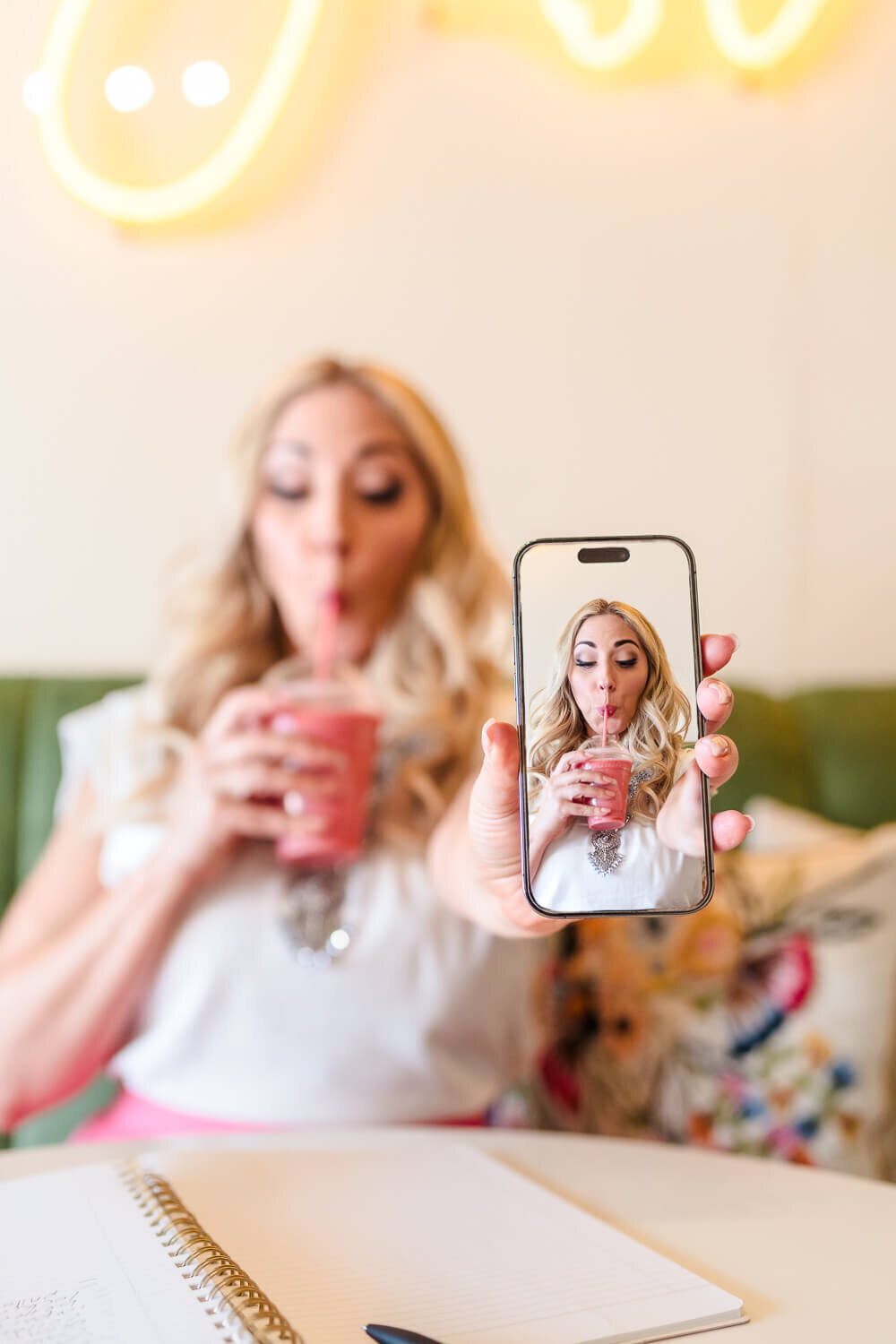 Local Kelowna businesswoman drinking a smoothie and holding her phone during brand photoshoot at Just Peachy.