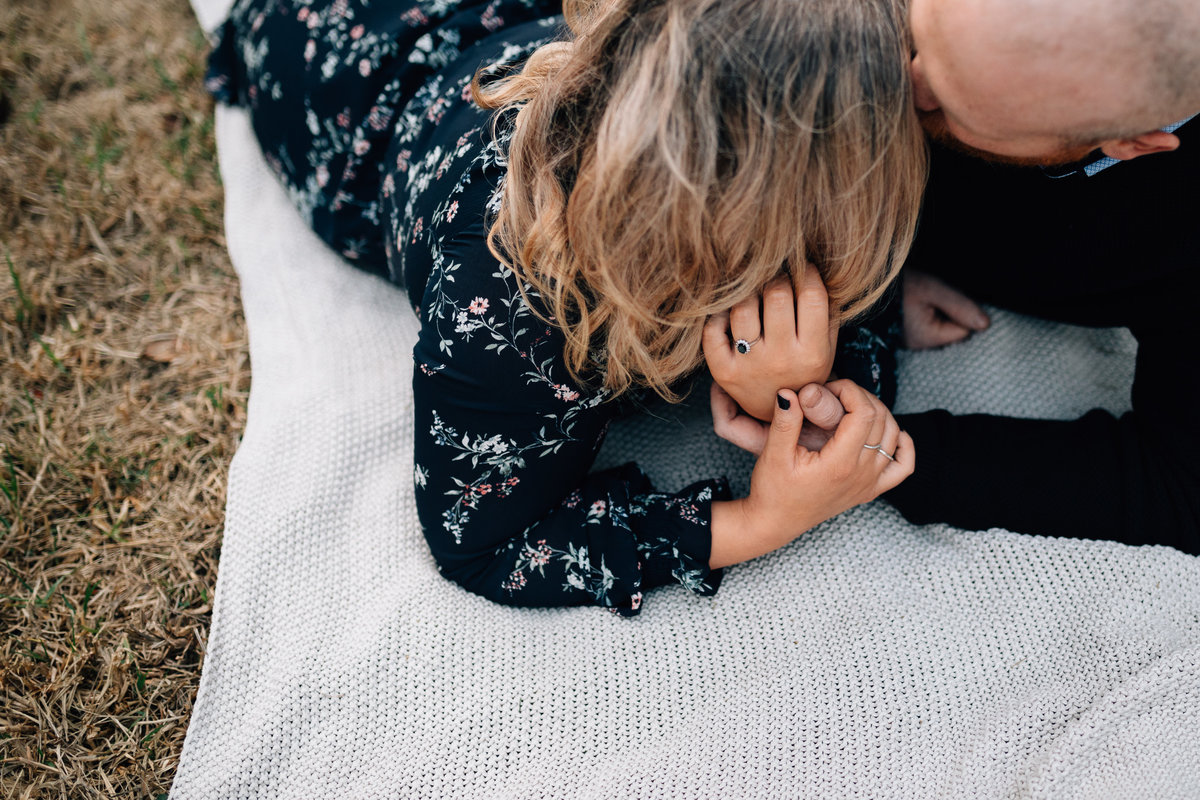 Looking down on man with hand in woman's hair, laying on picnic rug. Couples photography Melbourne, And So I Don’t Forget Photography