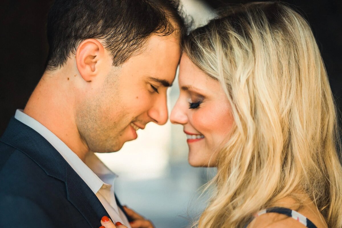 Close-up of a couple almost kissing, with focus on their smiling faces bathed in golden light