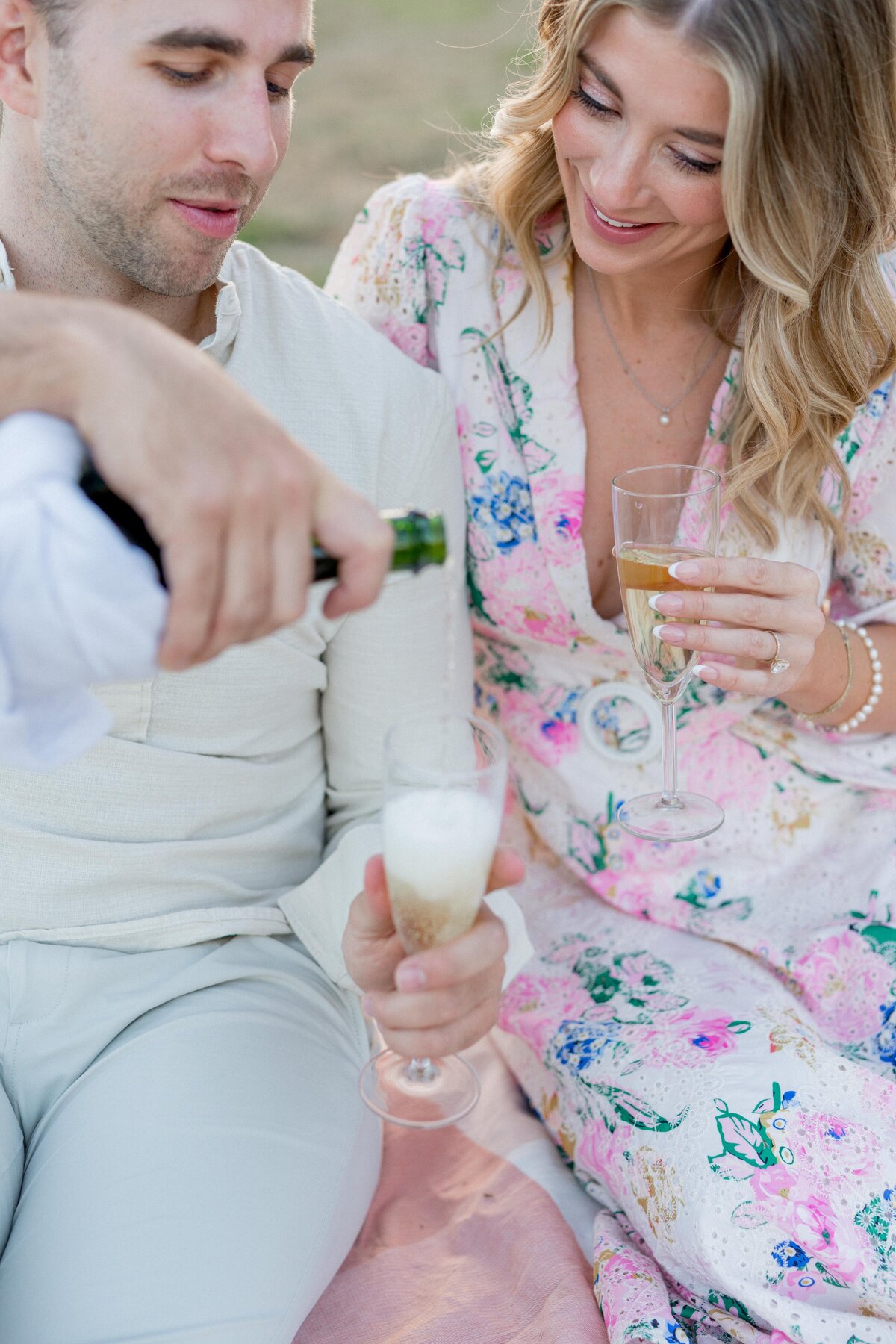 Close-up of couple pouring champagne during picnic
