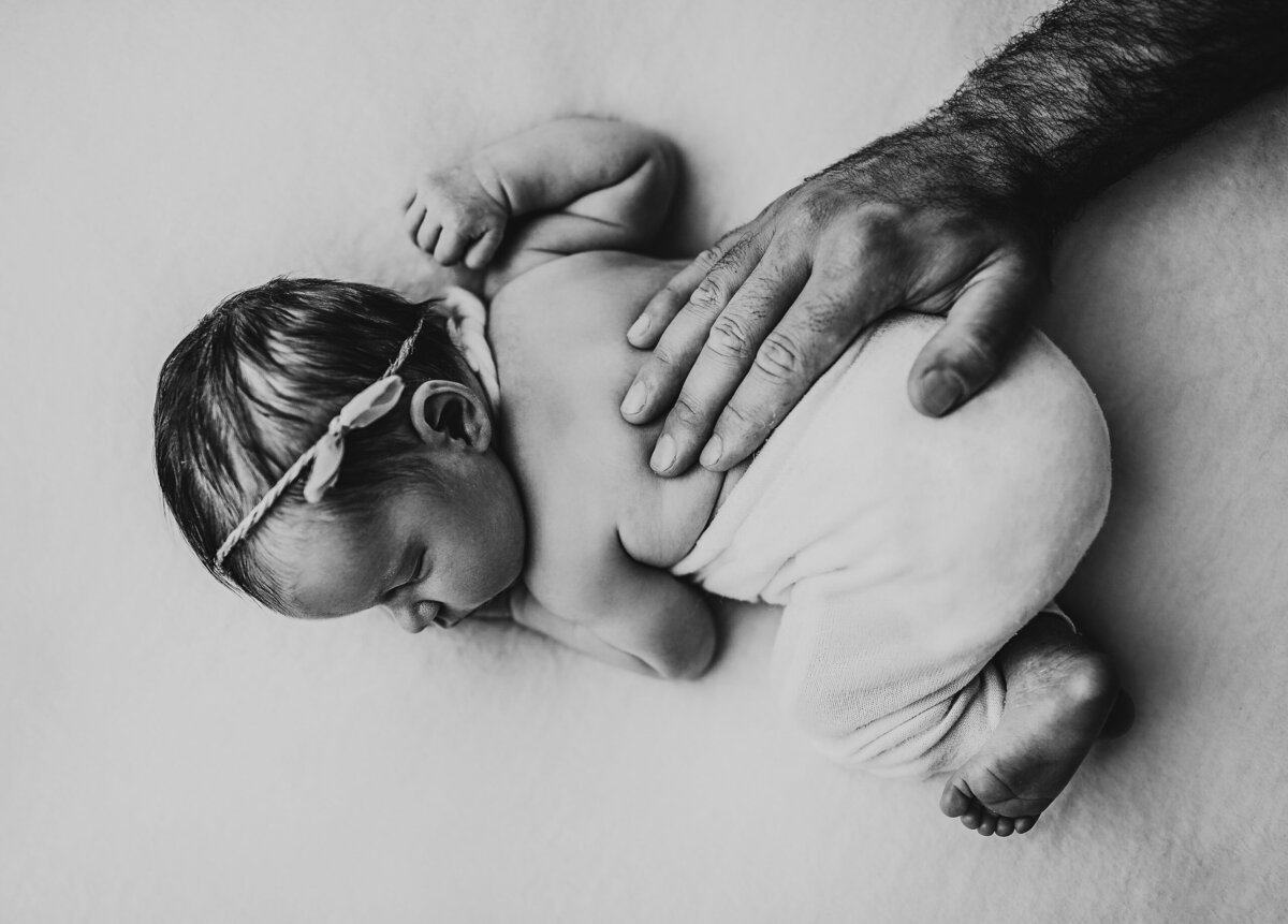black and white image - dad's hand on newborn's back, Cockburn newborn photographer