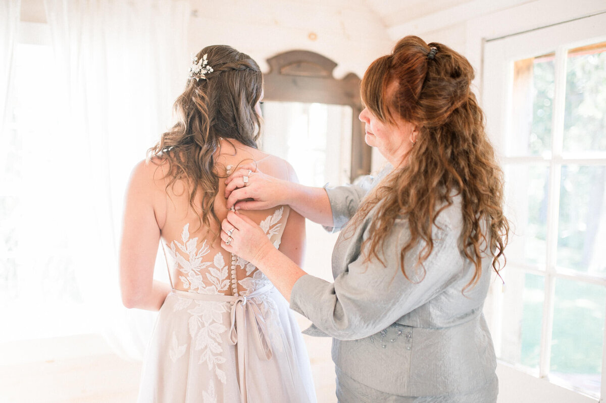 Brides mom helps button up wedding dress