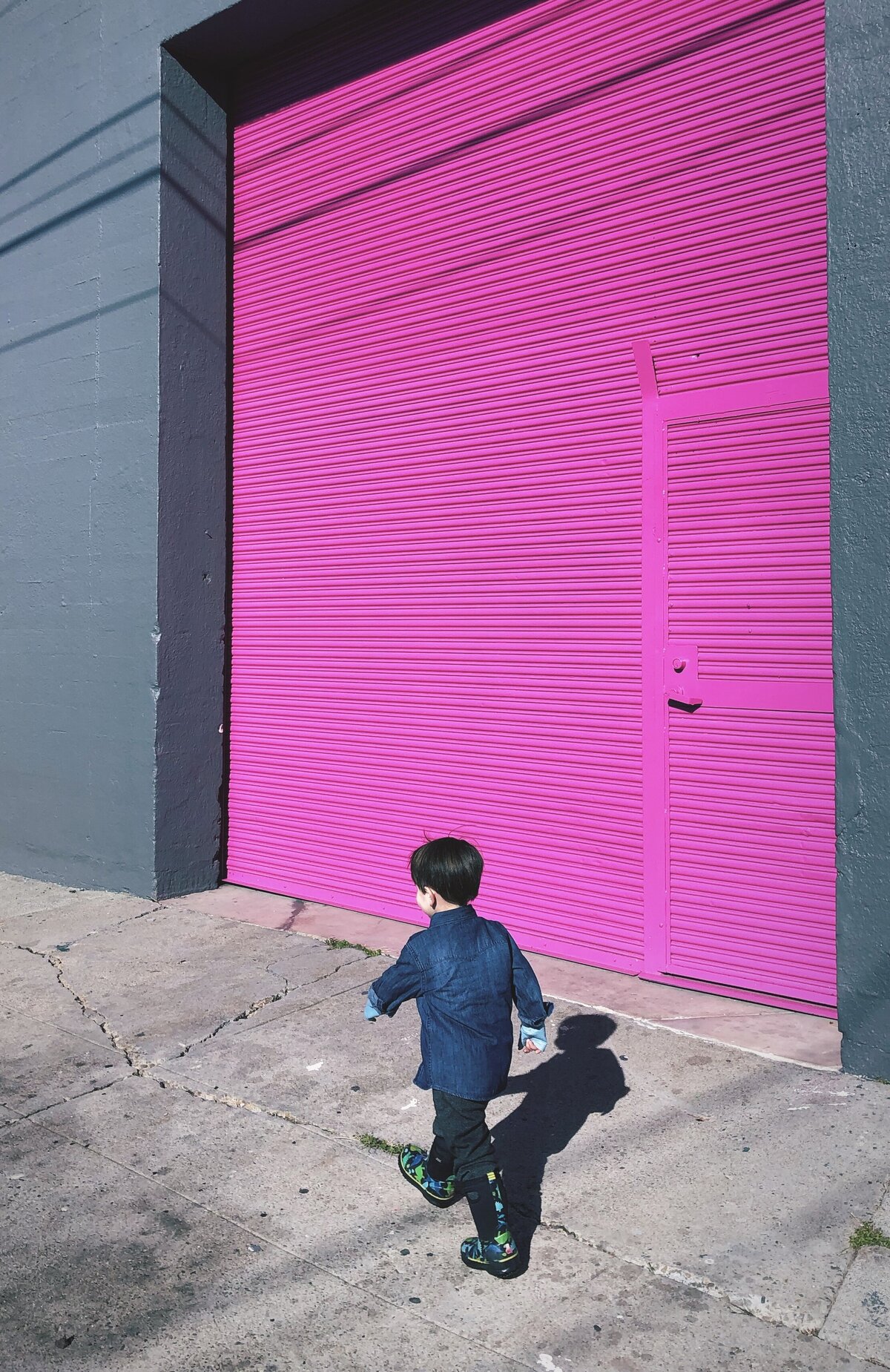 Boy walks in front of a magenta colored door