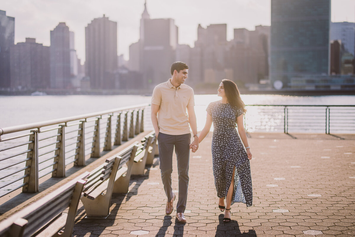 A couple walking down the promenade at gantry plaza in nyc during their engagement shoot