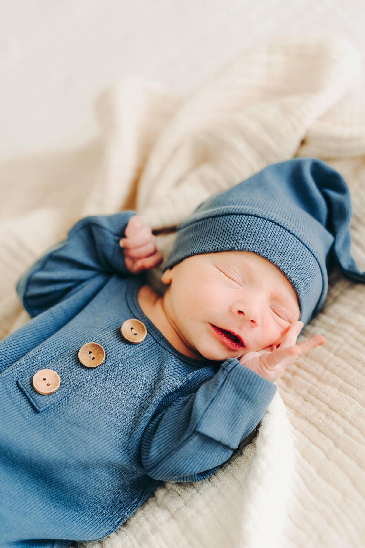 baby boy sleeps during newborn session in a blue hat and gown