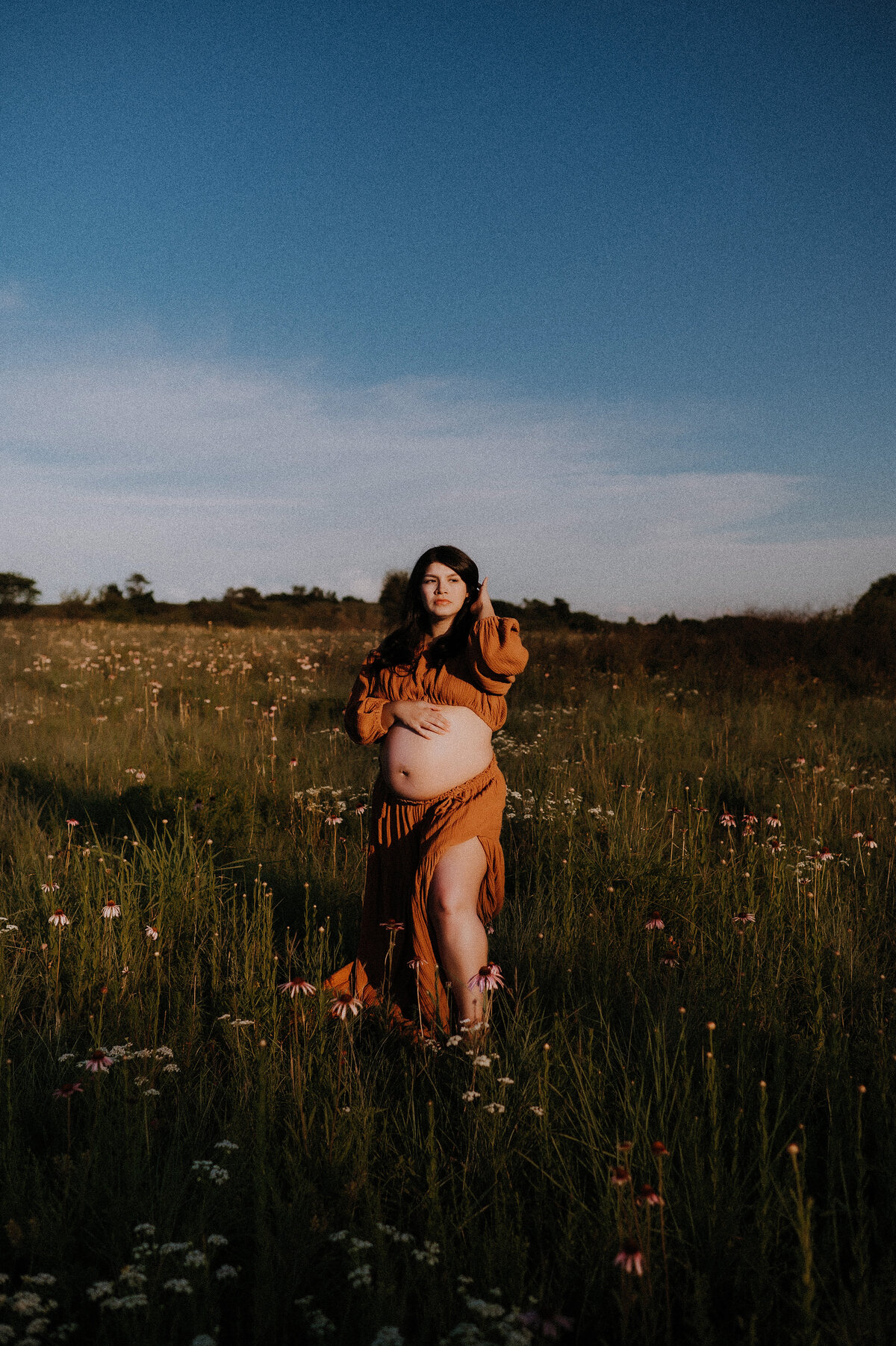 A bare belly pregnant woman standing in a field of purple texas wildflowers in Fort Worth, Texas