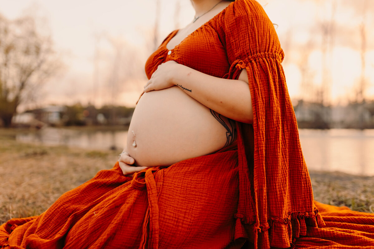 Maternity photography in Cleveland TX - close-up of pregnant belly in burnt orange gown outdoors
