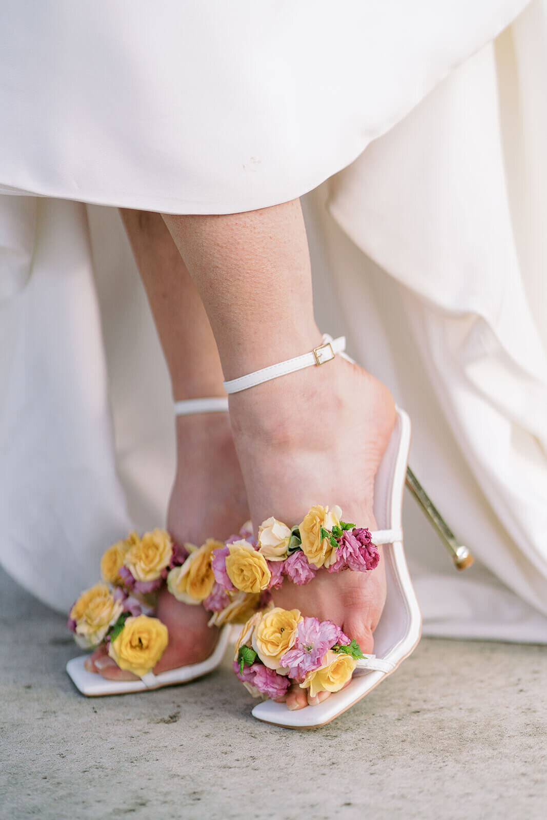 closeup of bride wearing luxury wedding shoes decorated with real yellow and pink flowers at her wedding at blenheim palace