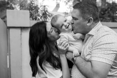 Happy family of four poses on cobblestone path during outdoor family photography session in St Augustine FL