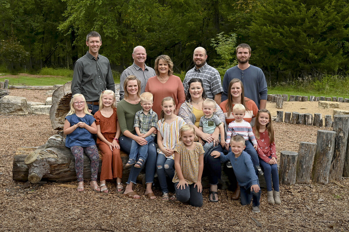 An extended family sit close together on tree stumps