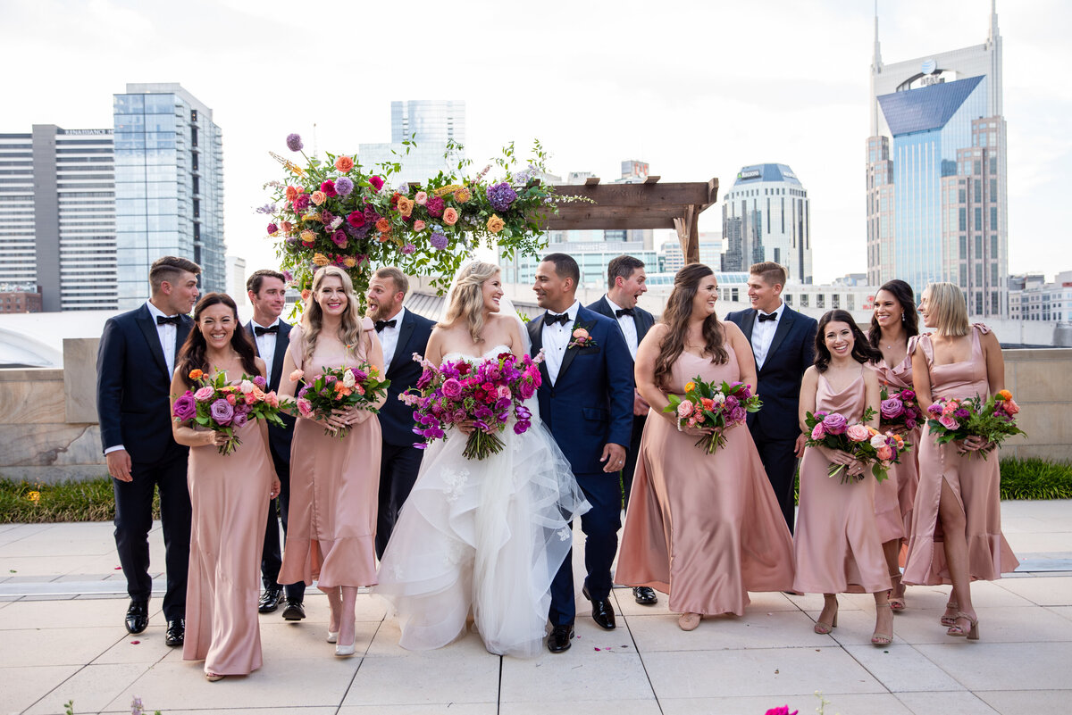 Vibrant bridesmaid bouquets accenting sunset color pallet with hues of lavender, orange, and golden yellow composed of petal heavy roses and ranunculus. Design by Rosemary and Finch in Nashville, TN.