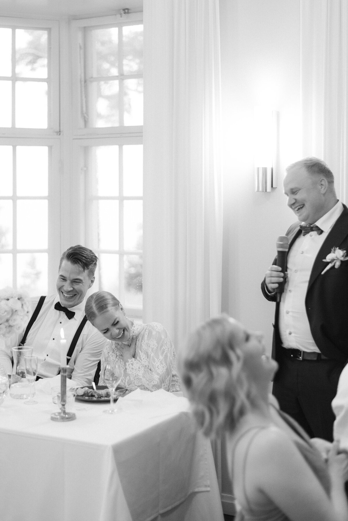 Documentary wedding photograph of a wedding guest giving a speech to bride and groom in Airisniemi manor in Turku, Finland. Atmosphere captured by wedding photographer Hannika Gabrielsson.