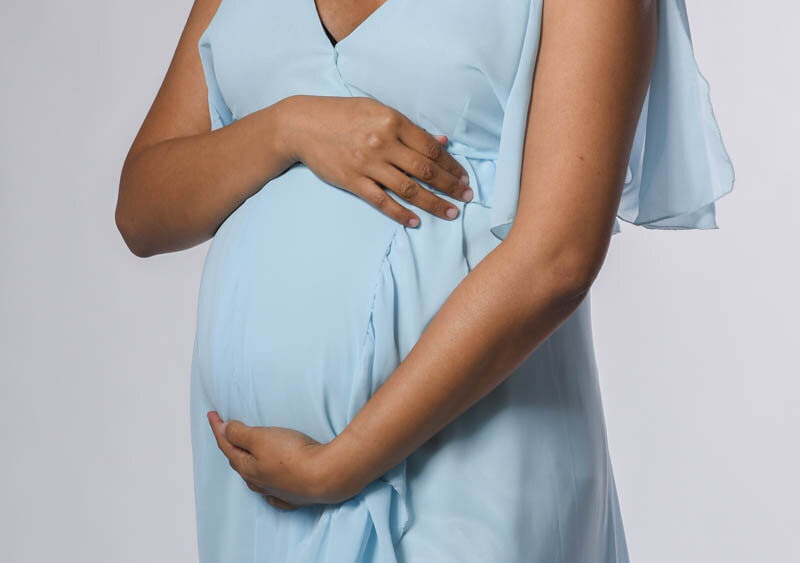 Photograph of a pregnany woman's belly bump with her hands wrapped around her belly