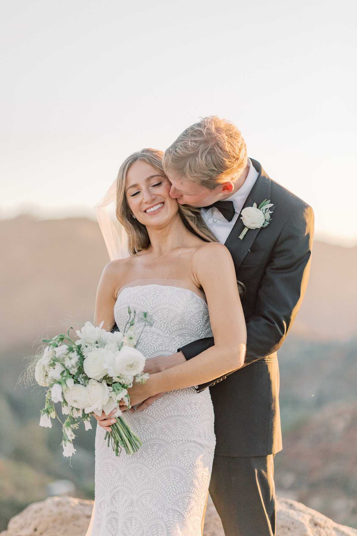 Groom-Kissing-Bride-White-Flowers