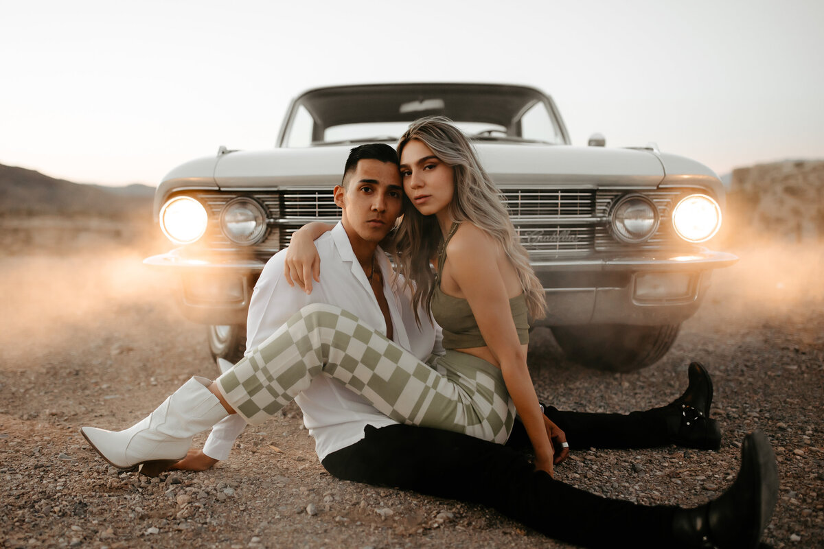 Couple embracing in red rock canyon with classic car