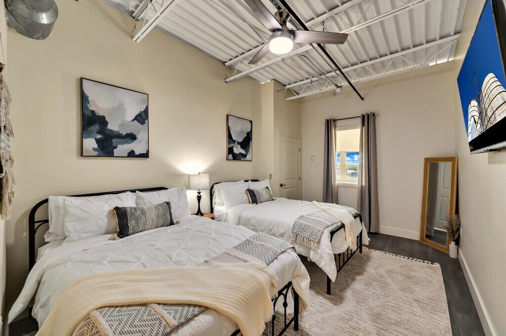 Bedroom with two queen beds and smart TV in this 2 bedroom, 2.5 bathroom luxury vacation rental loft condo for 8 guests with incredible downtown views, free parking, free wifi and professional decor in downtown Waco, TX.