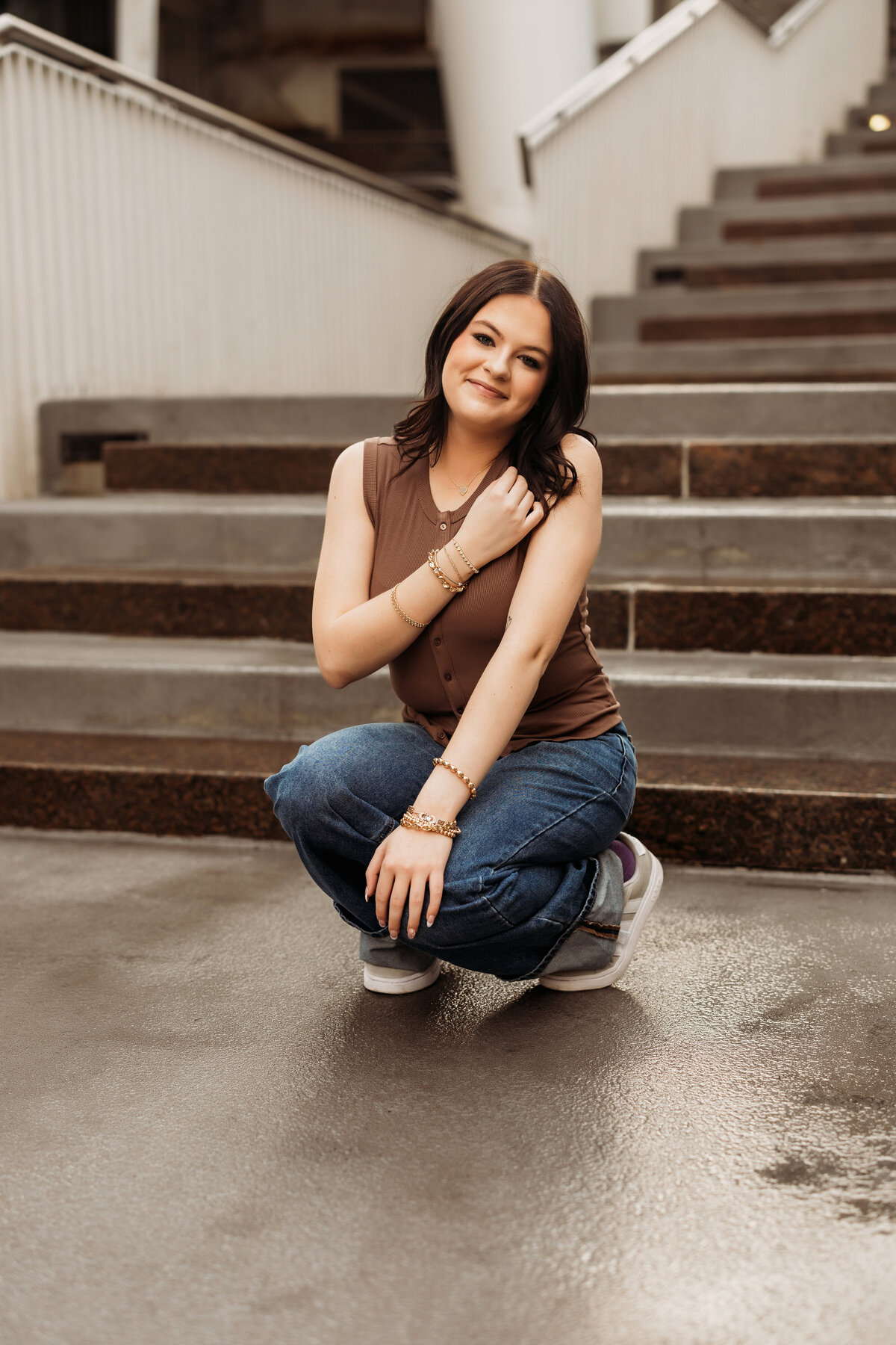 high school senior girl squats on concrete steps in downtown Denver for her urban photo session