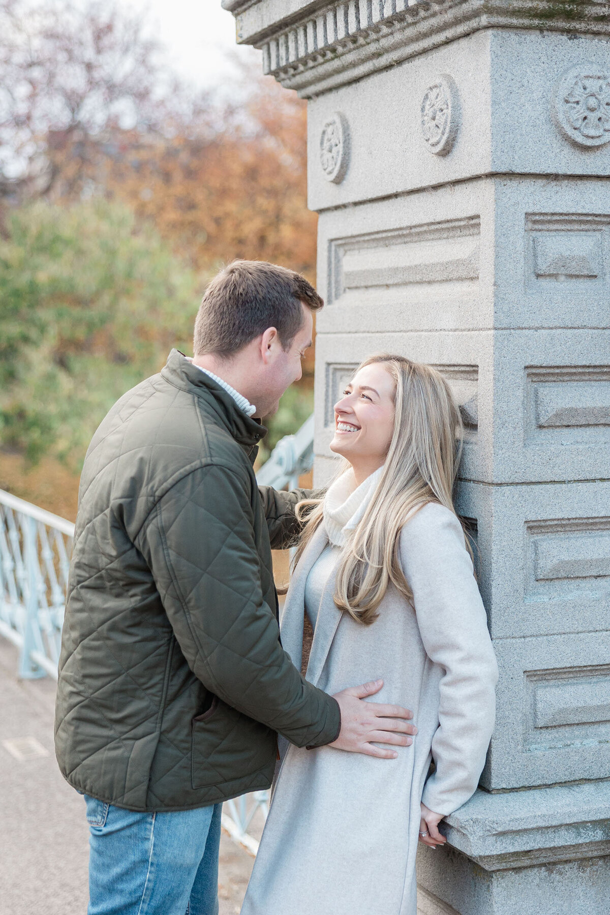 A man leans into his fiancee on the bridge of the Boston Public Gardens