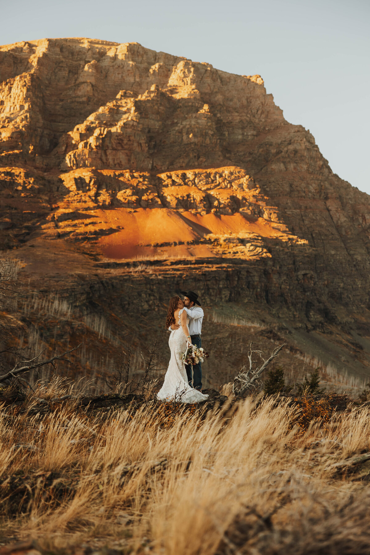 bride and groom kissing in front of mountain