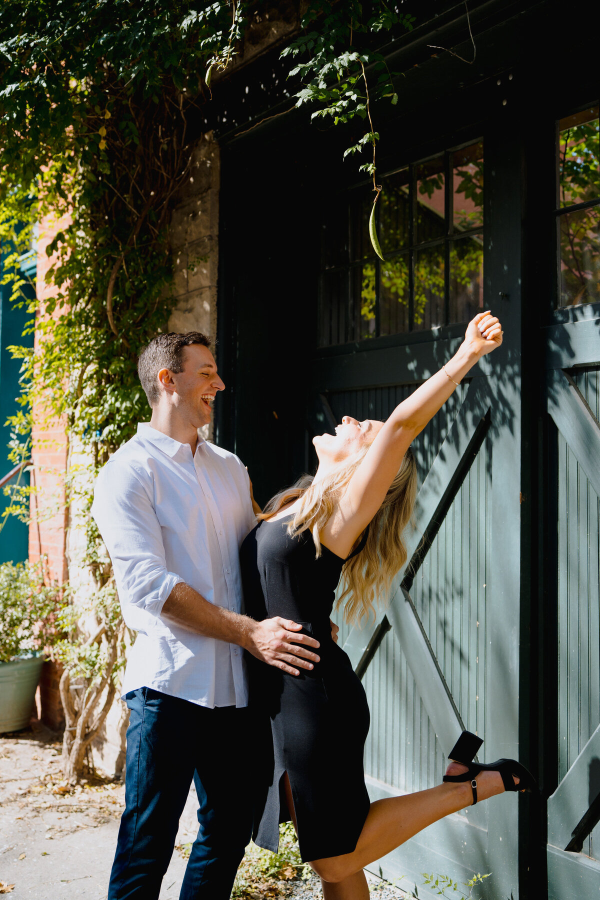 A man with his arms around a woman's waist as she kicks one foot back and leans back.