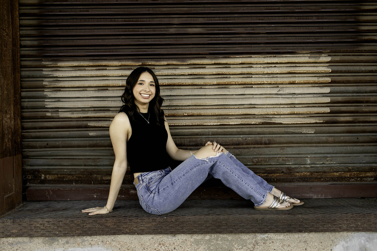 A senior student sits with their legs stretched out, relaxed and comfortable in their photoshoot