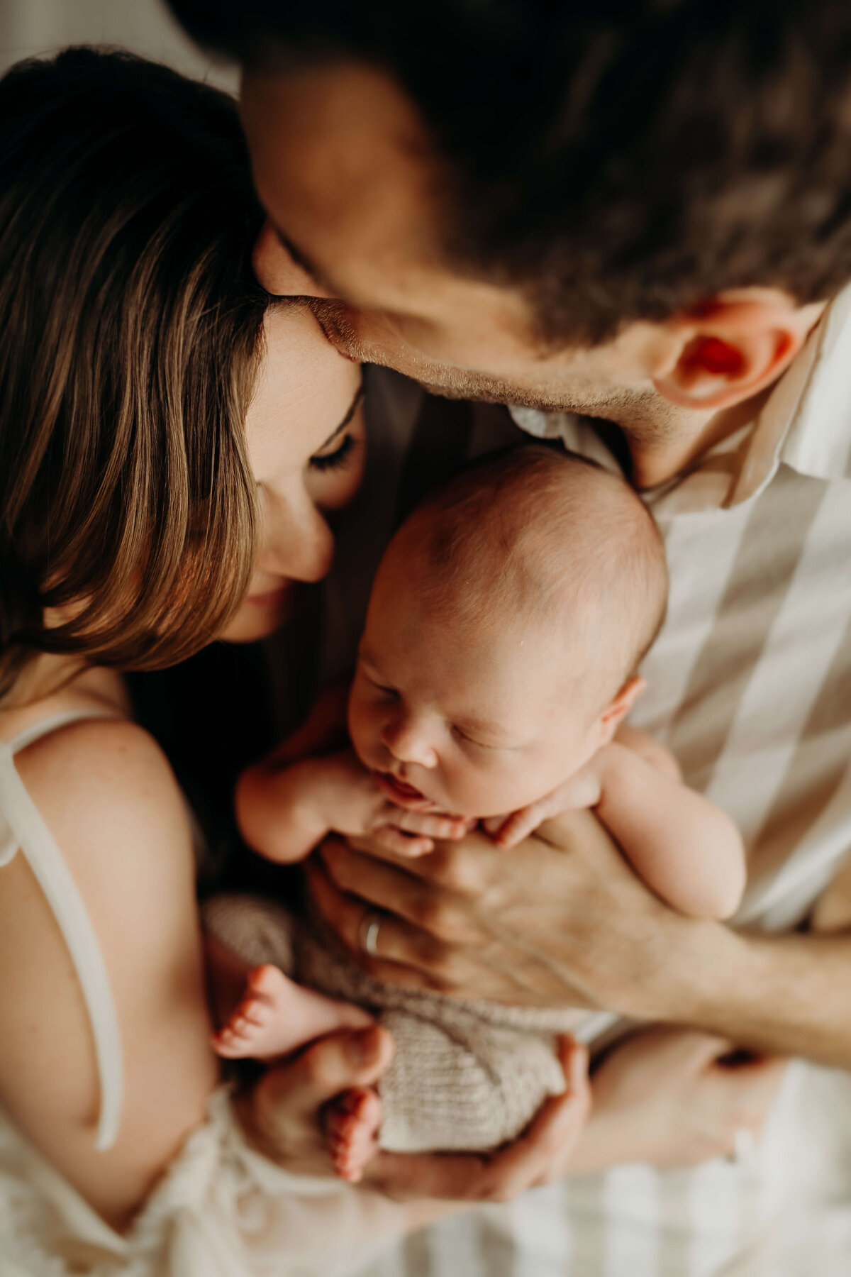 dad kisses moms forehead as he holds their newborn son