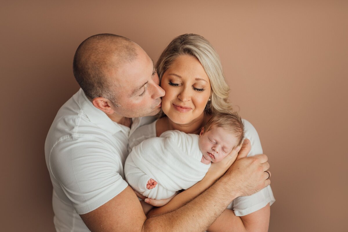 mom and dad hold baby during photography session in tampa bay