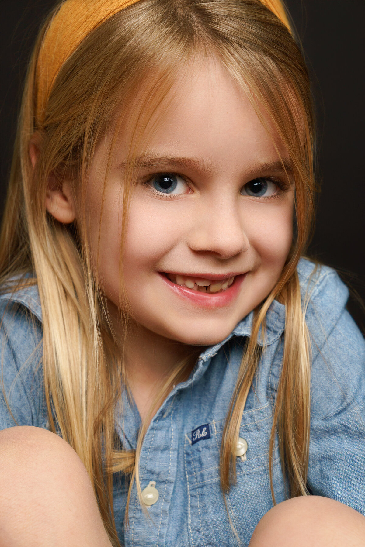 Extreme Closeup portrait of young girl wearing denim Ralph Lauren Polo Dress with blonde hair and blue eyes
