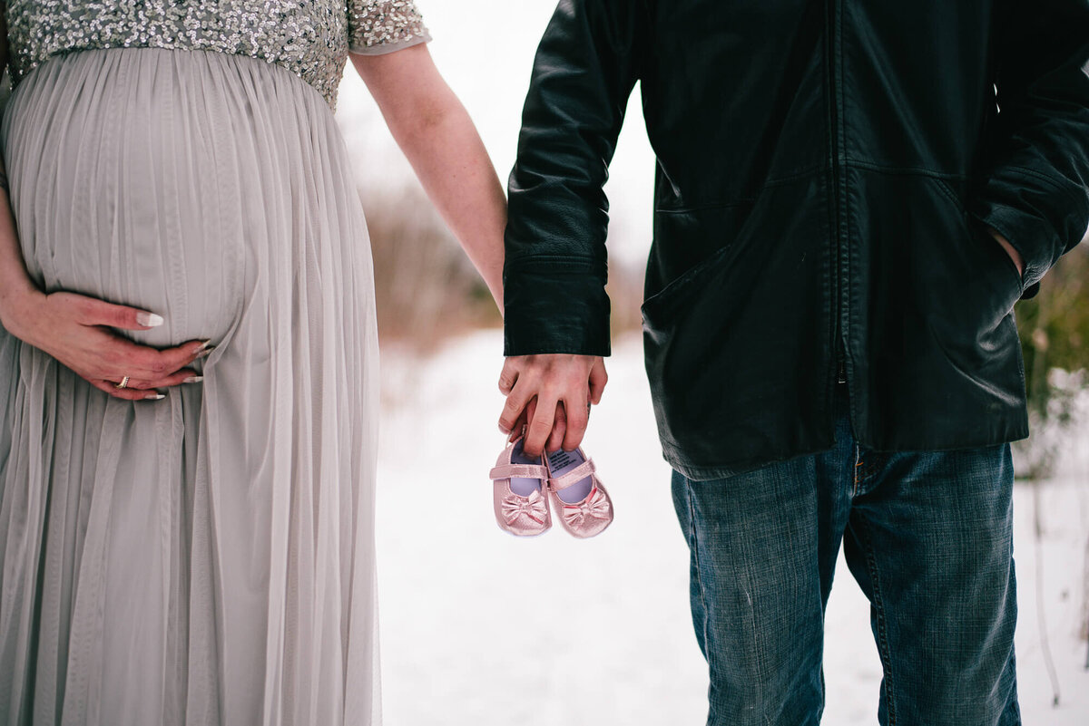 Expecting couple holding baby shoes in Toronto maternity photography