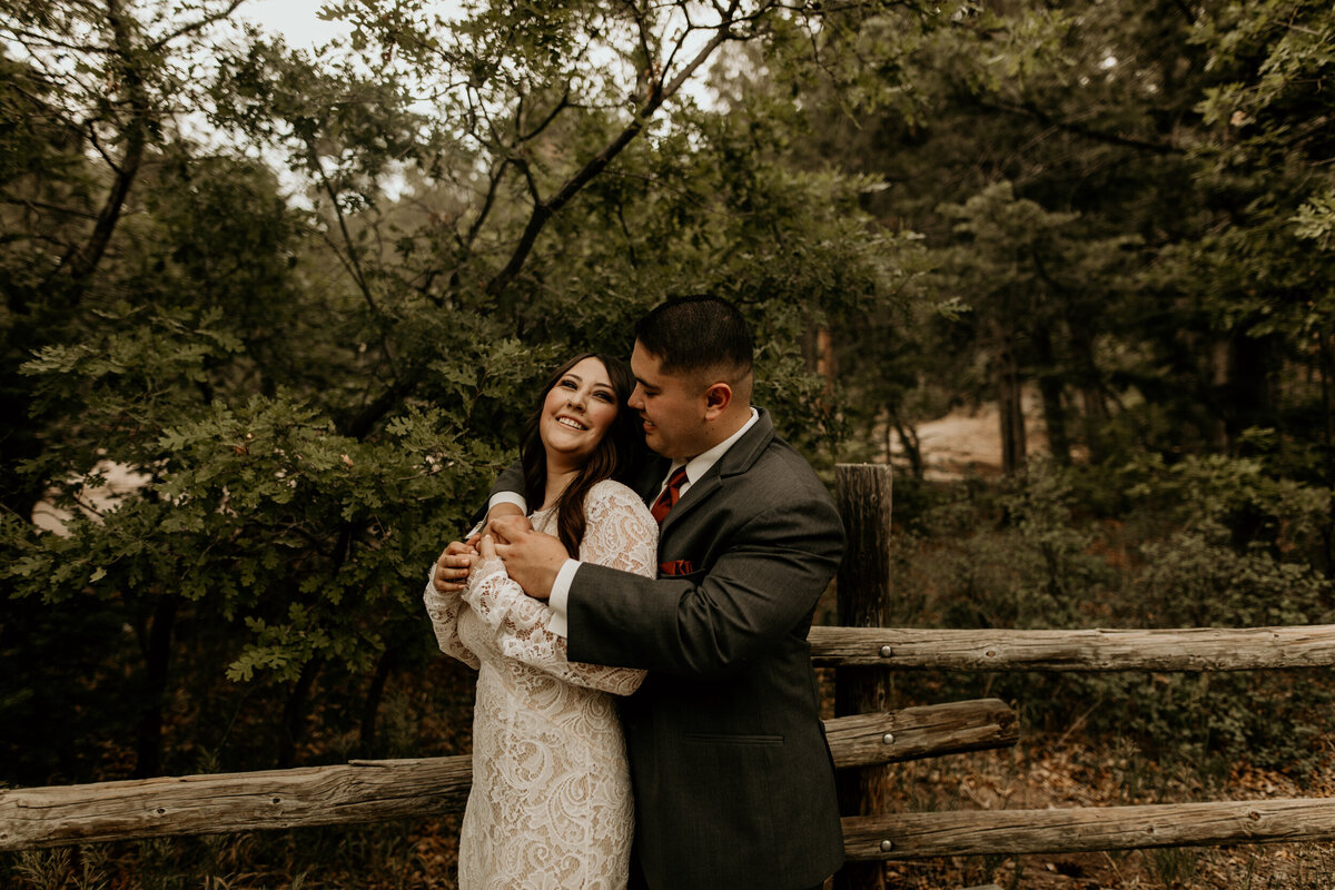 newlyweds leaning against a fence together in new Mexico